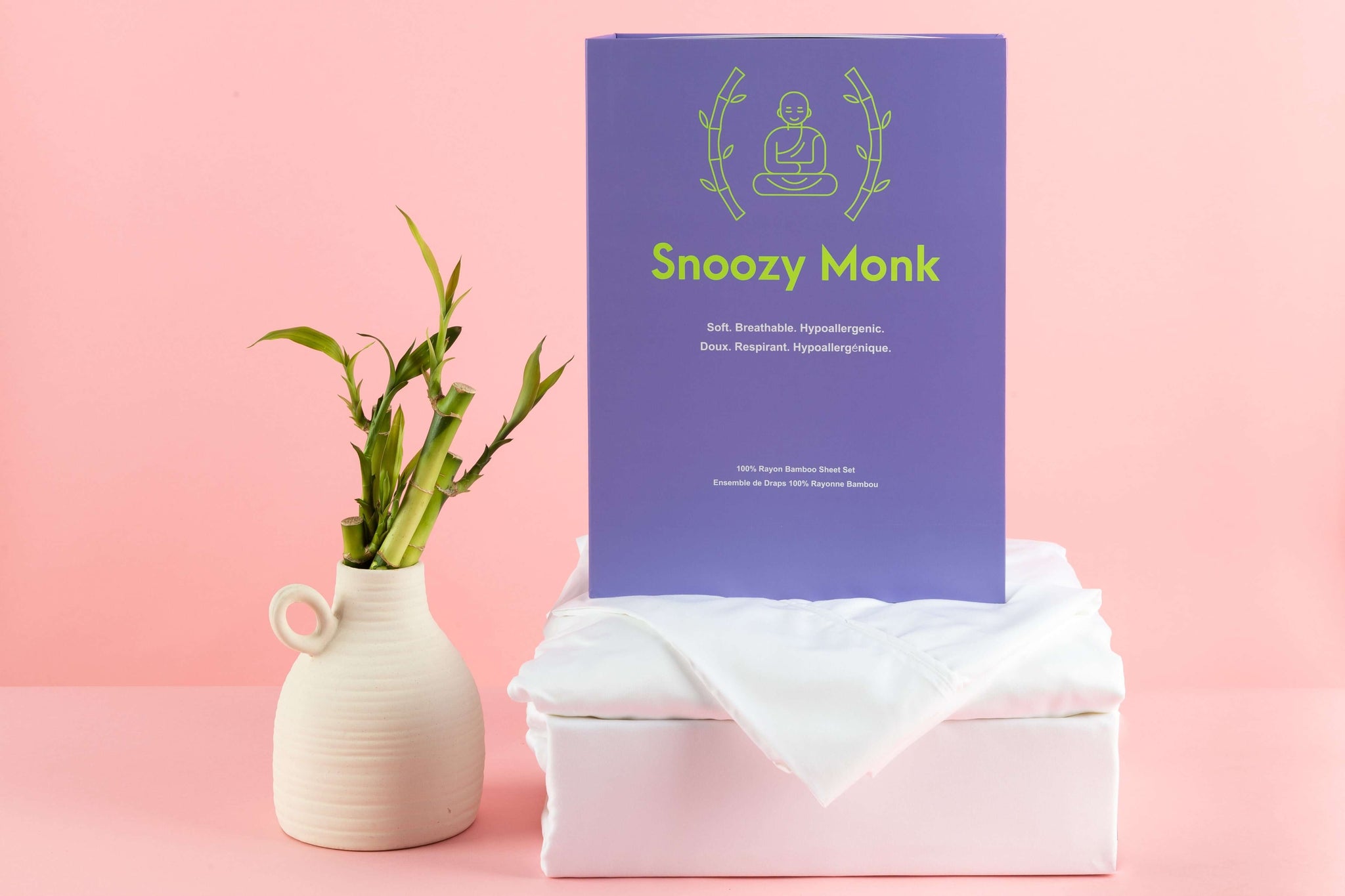A White Snoozy Monk Rayon Bamboo Sheet Set with a decorative background and bamboo stalks